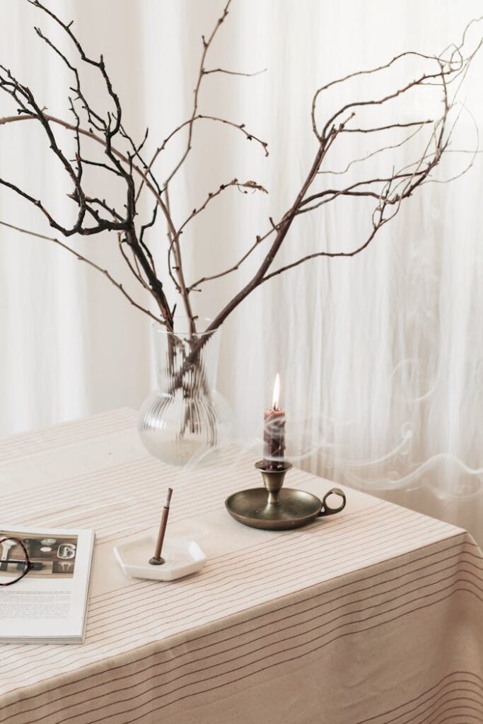 A serene, vintage-inspired table setting with a candle, twigs, and rustic decor.